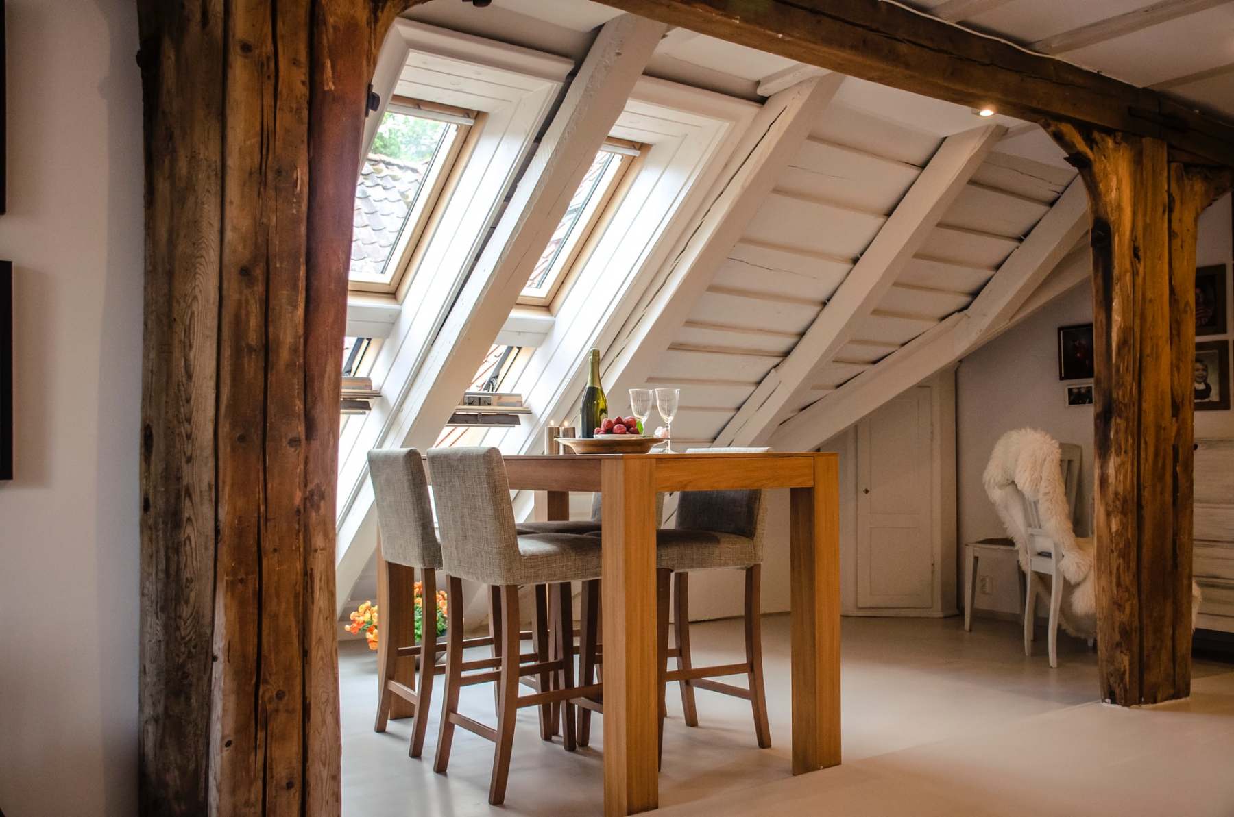 loft conversion with white beams, light brown furniture and large velux windows